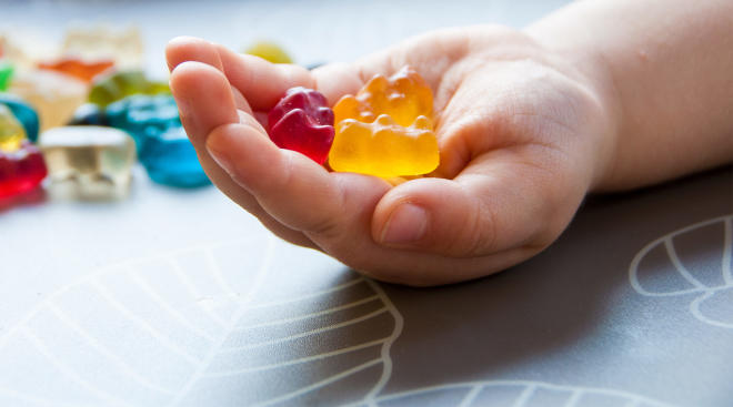 child holds gummy vitamins in hand