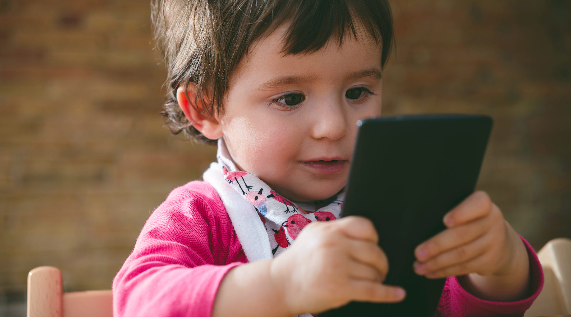 toddler looking happily at phone screen
