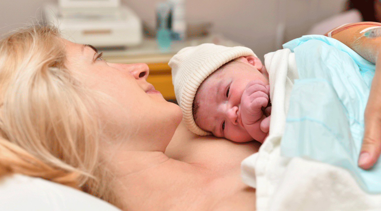 mom holding newborn baby after birth in hospital bed