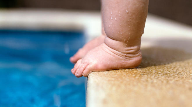 toddler's feet stand too close to edge of pool