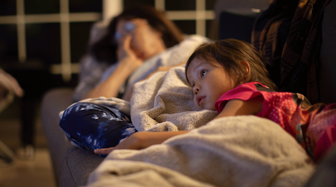 little girl watching TV with mom at night