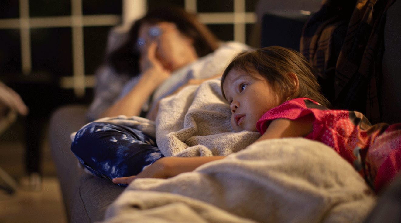 little girl watching TV with mom at night