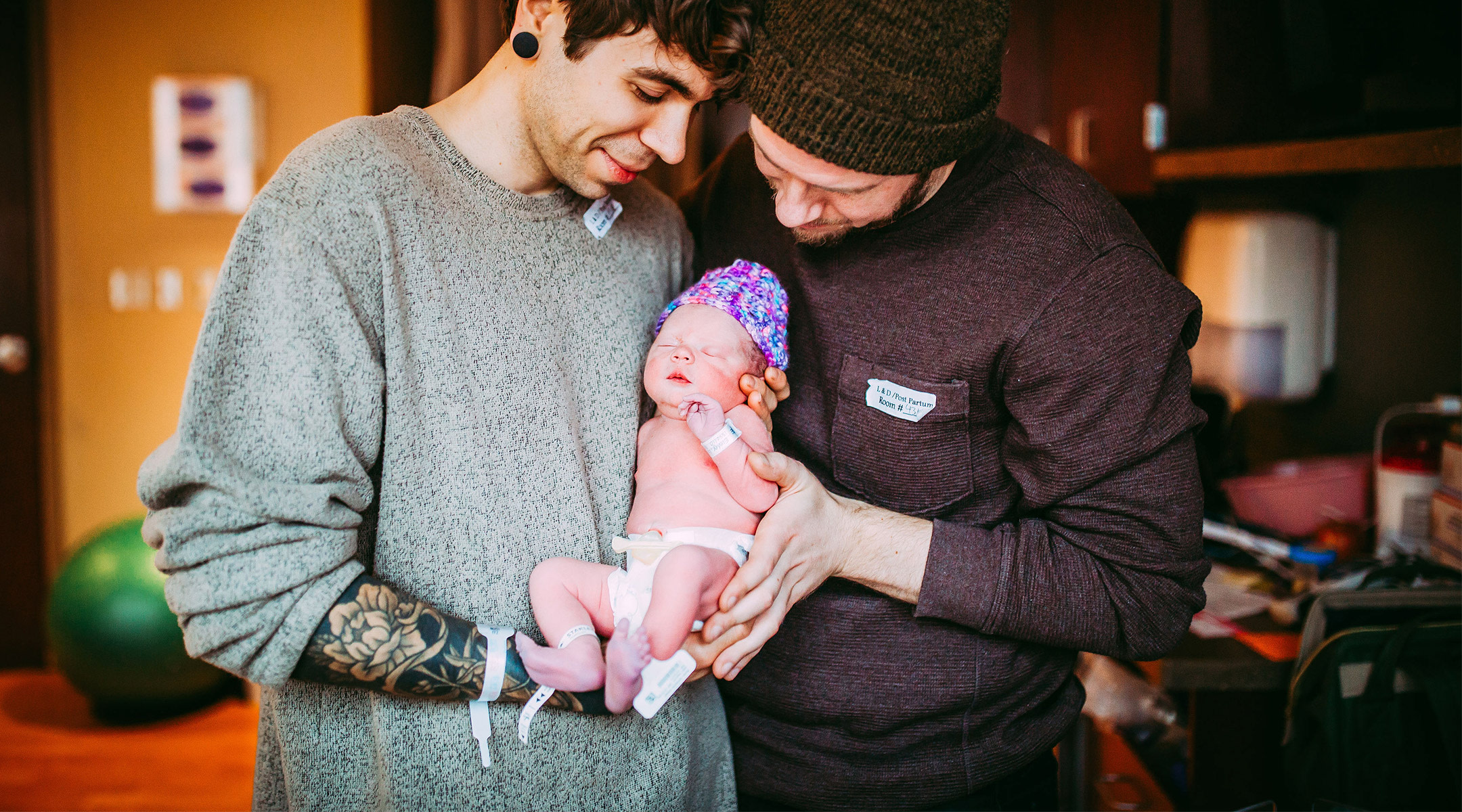 parents hold their newborn baby who was born via surrogate via their grandma