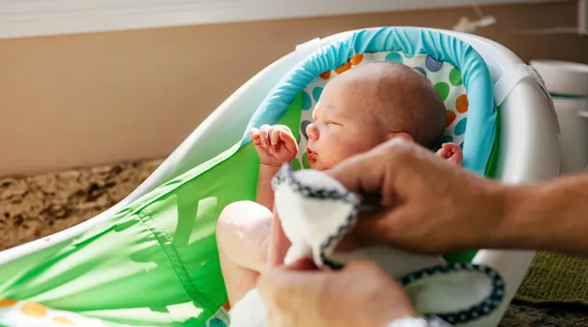 father bathing newborn baby in kitchen at home