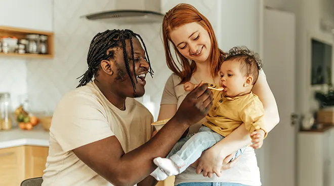 parents feeding baby food at home