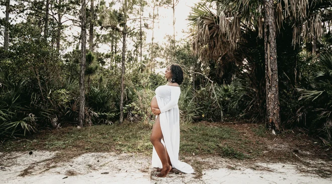 black pregnant woman in white dress on a tropical island