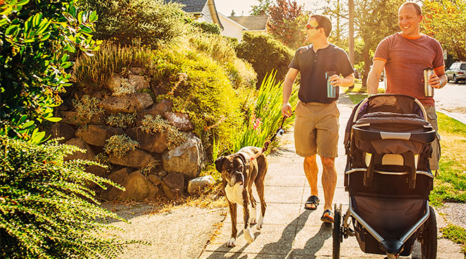 dads walking their baby in a stroller in residential neighborhood