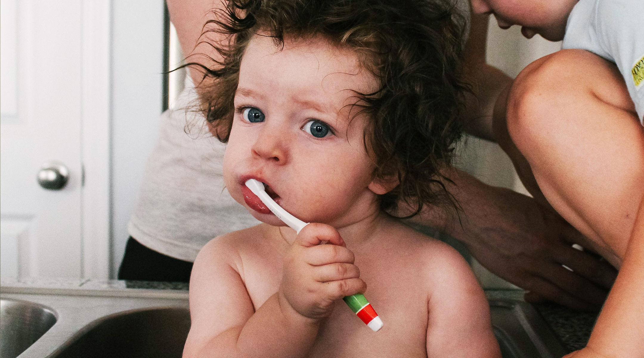 toddler brushing teeth in sink