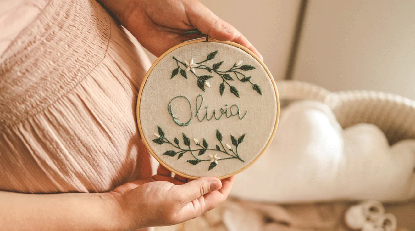 pregnant mom holding baby name sign that says Olivia