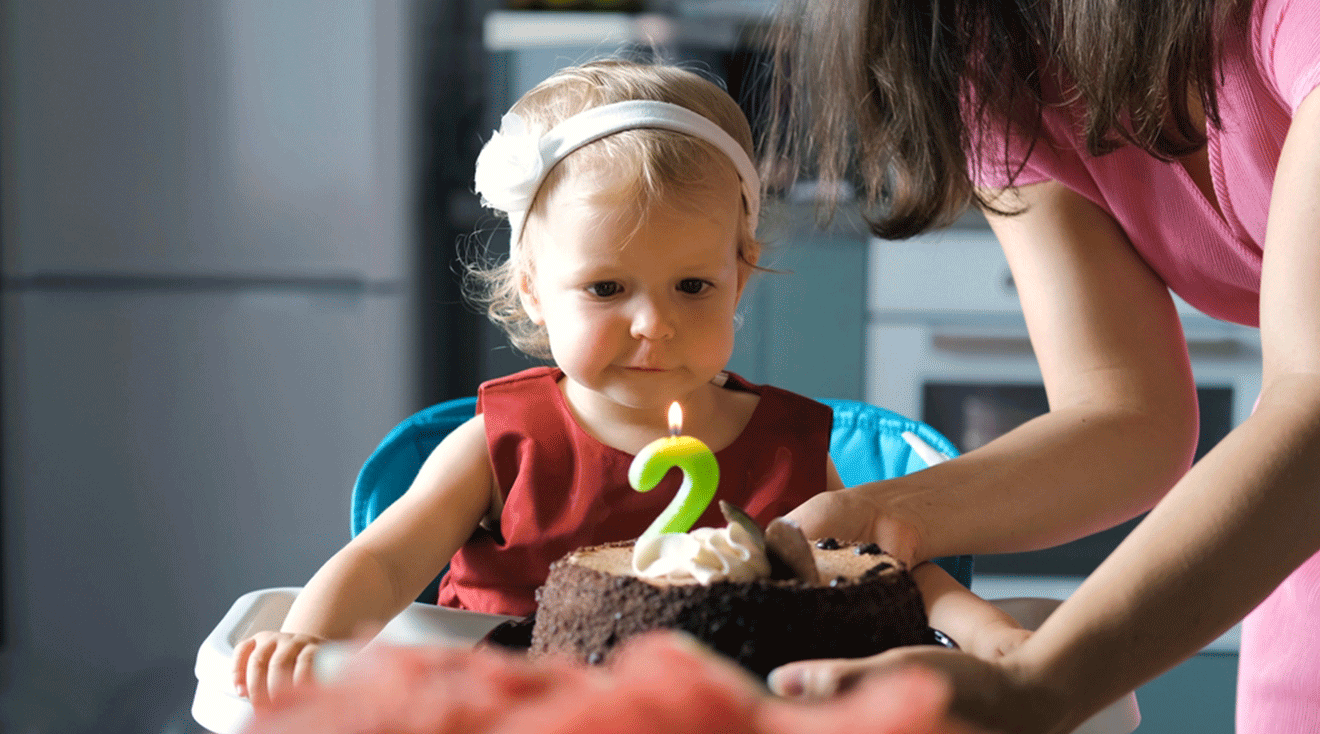 baby turning 2 with birthday cake at second birthday party