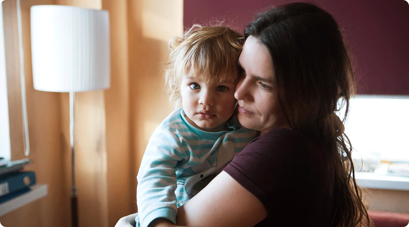 depressed mom holding toddler son at home