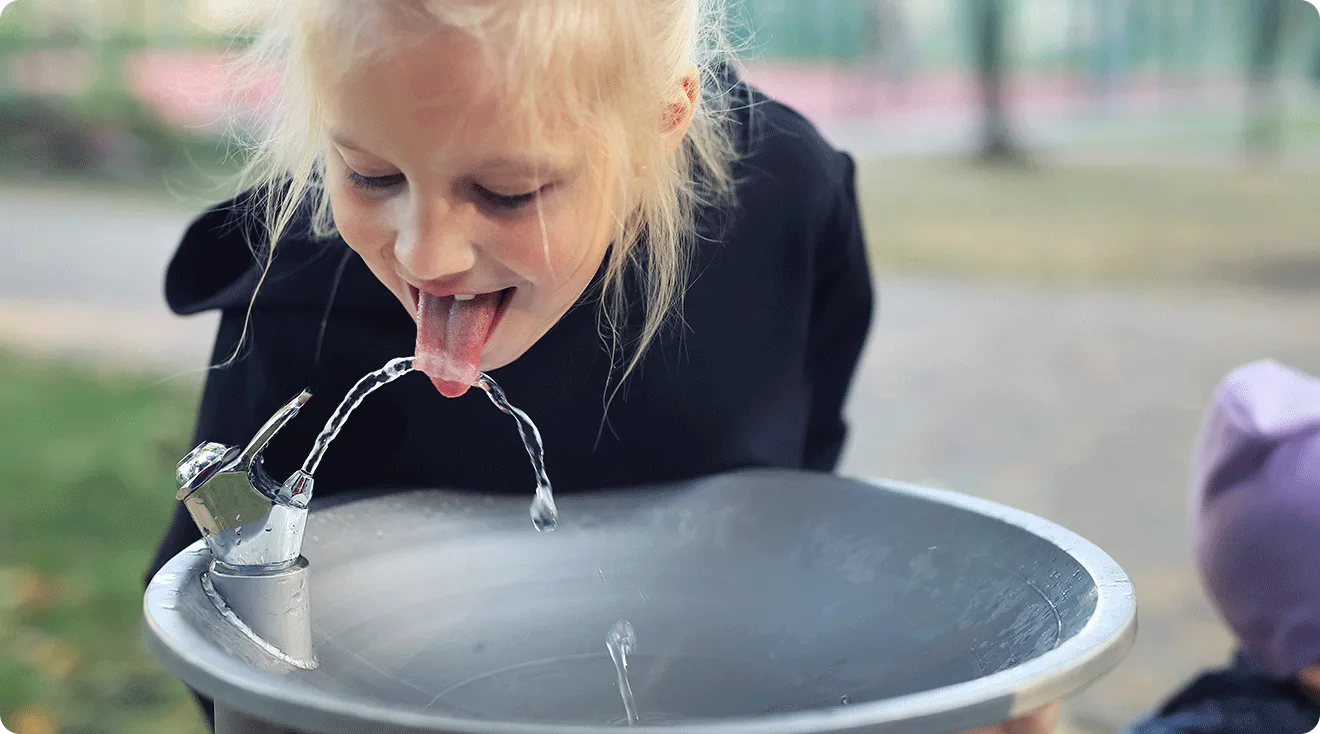 child drinking from water fountain