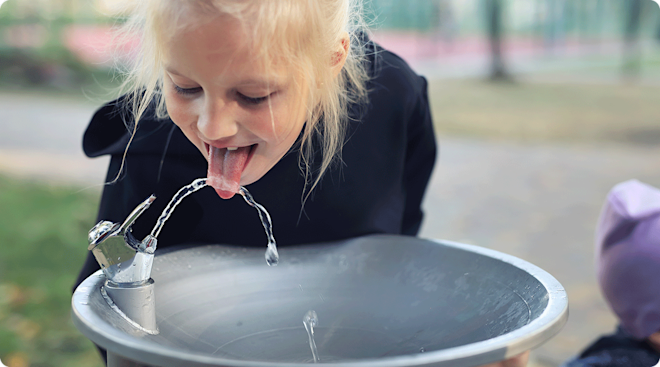 child drinking from water fountain