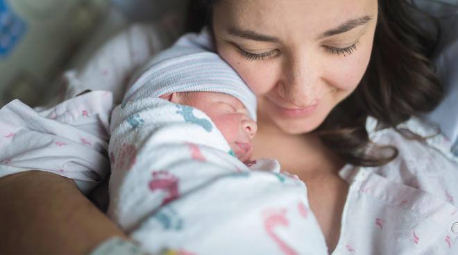 woman holds her new baby after giving birth