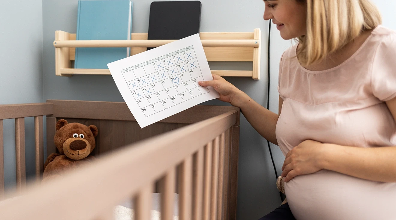 pregnant woman looking at calendar next to baby's crib
