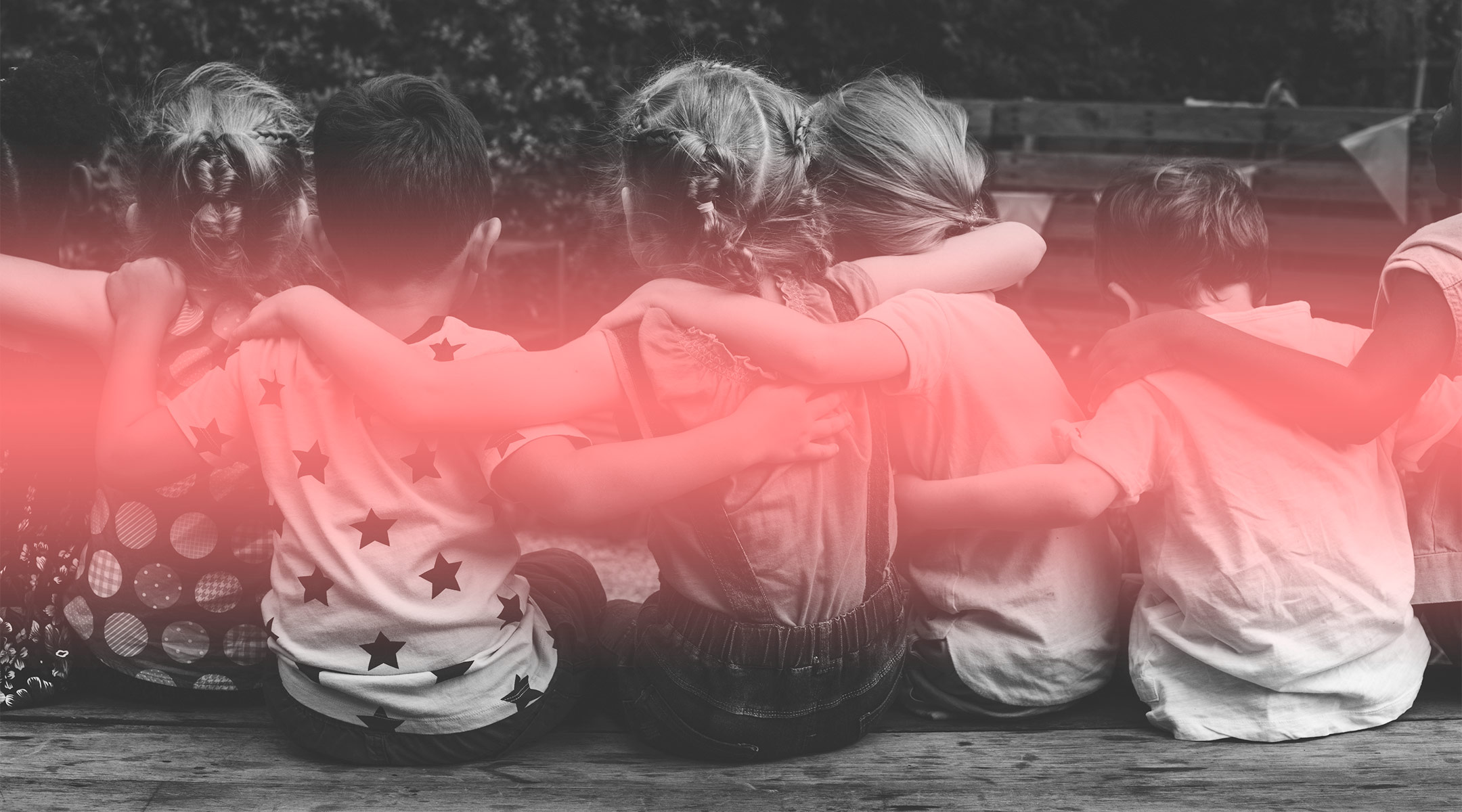 young school children sitting with their arms around each other