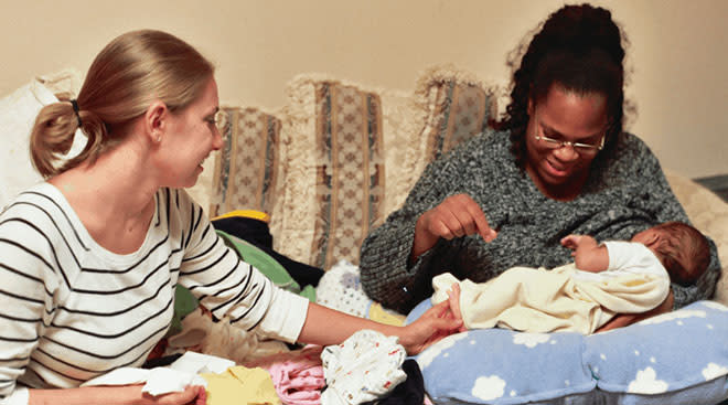doula helping a mother with her baby at home