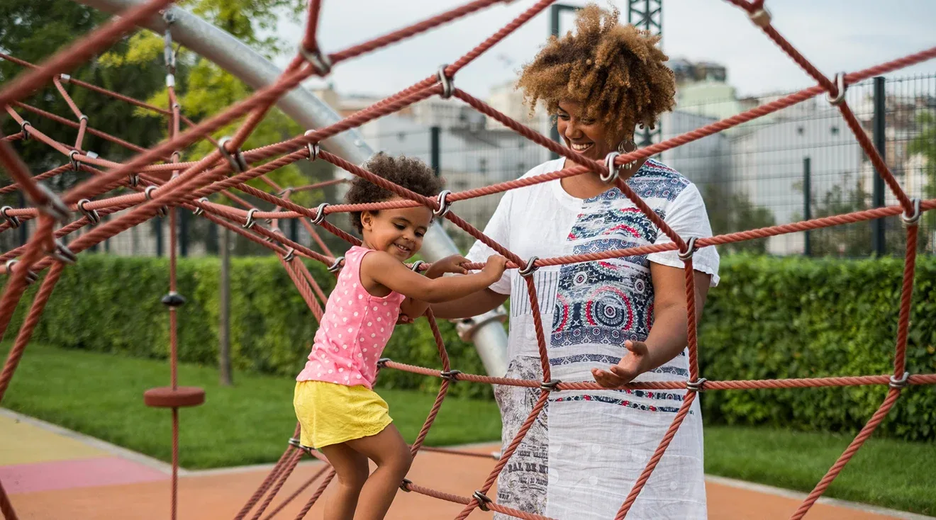 smiling mother watching happy toddler play on the playground
