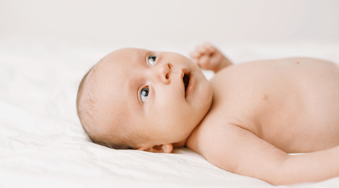 baby with blue eyes on bed at home