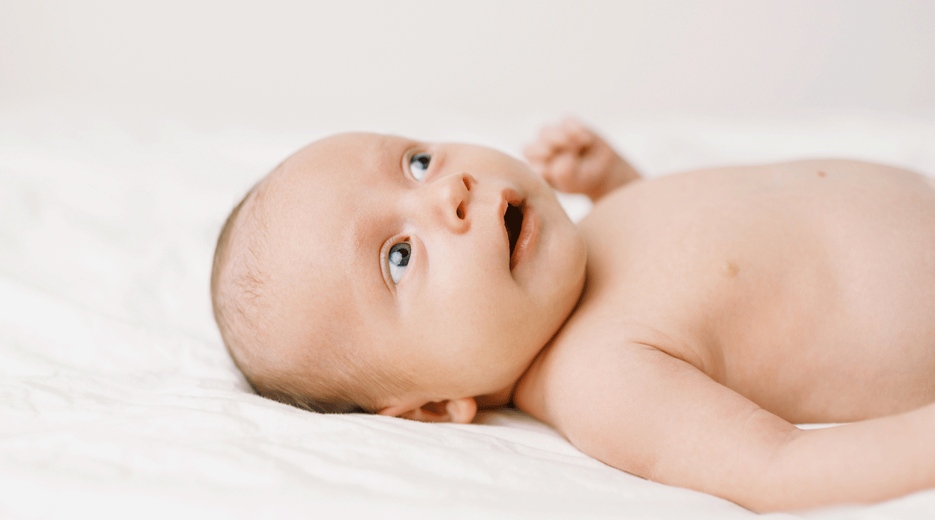 baby with blue eyes on bed at home