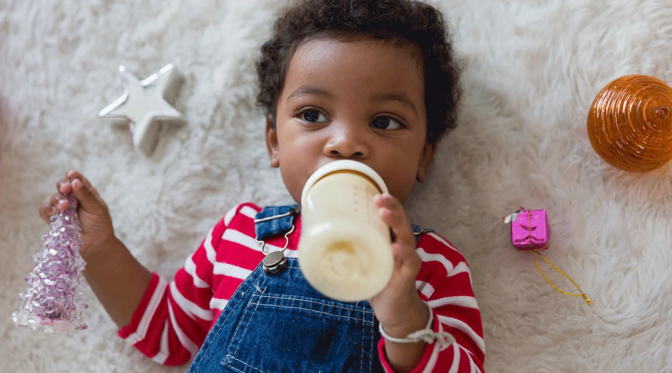 toddler boy drinking from bottle with milk