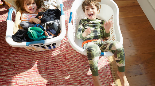 laughing kids having fun in laundry baskets at home