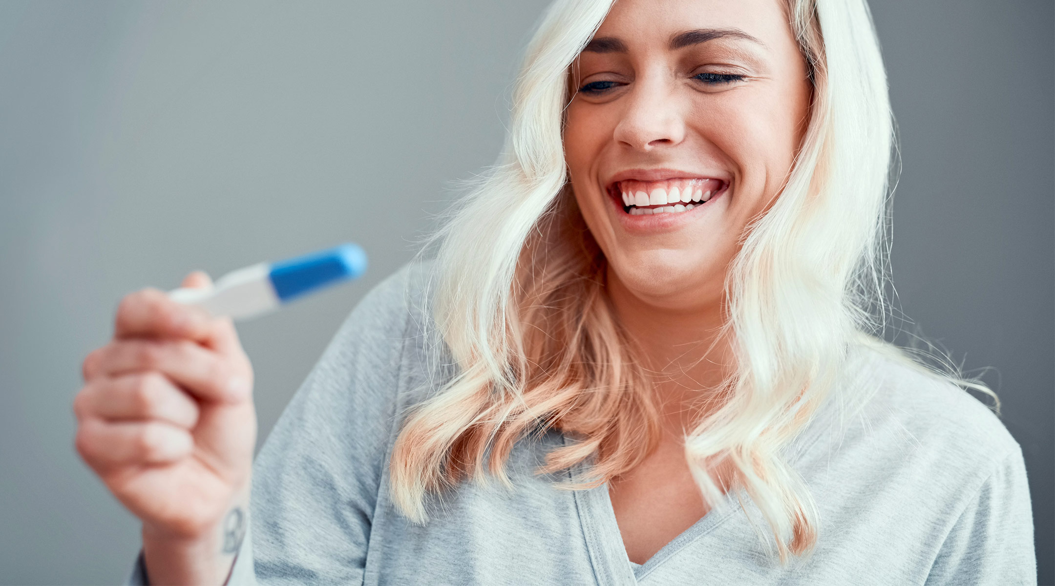happy woman holding positive pregnancy test