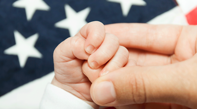 mom holding baby hand against American flag background