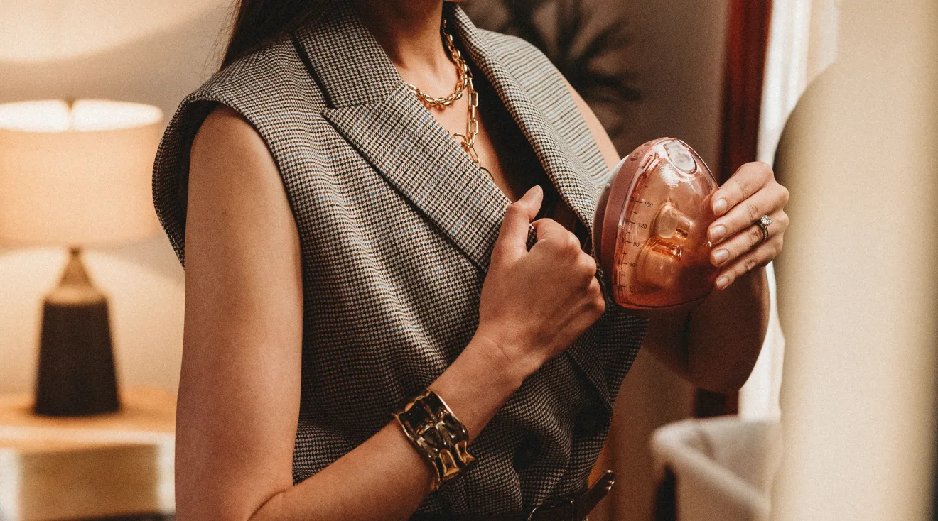 mom in work attire putting wearable breast pump inside shirt