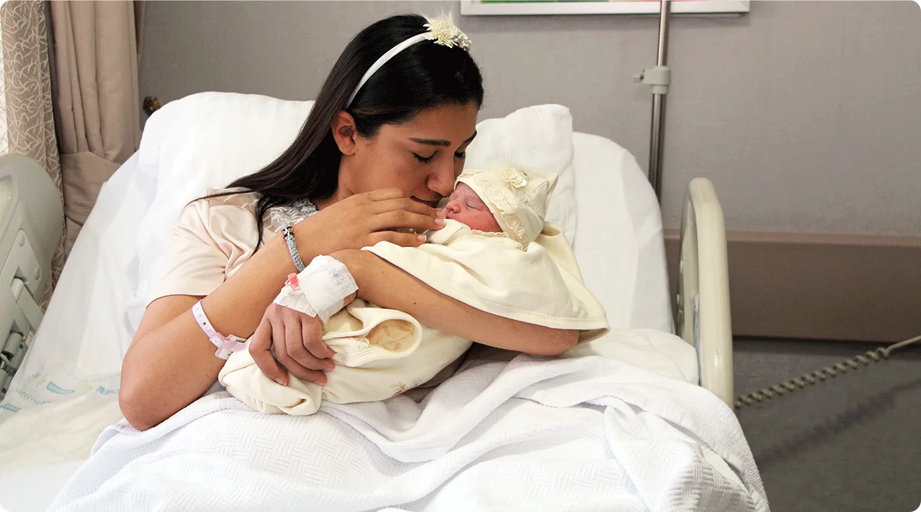 mother with newborn baby in hospital bed after giving birth