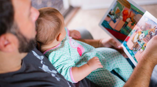 dad holding baby on his lap and reading to her