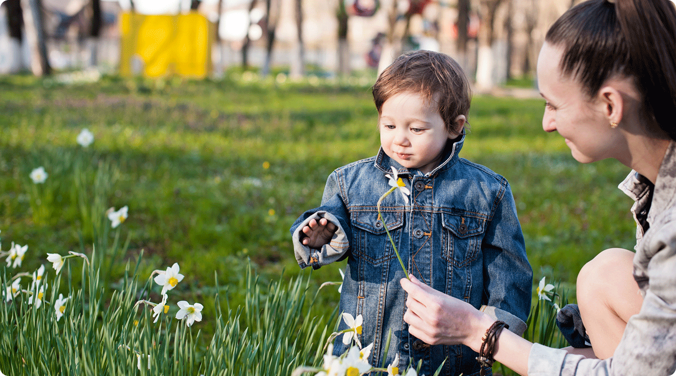 mom and baby looking at daffodil flowers outside