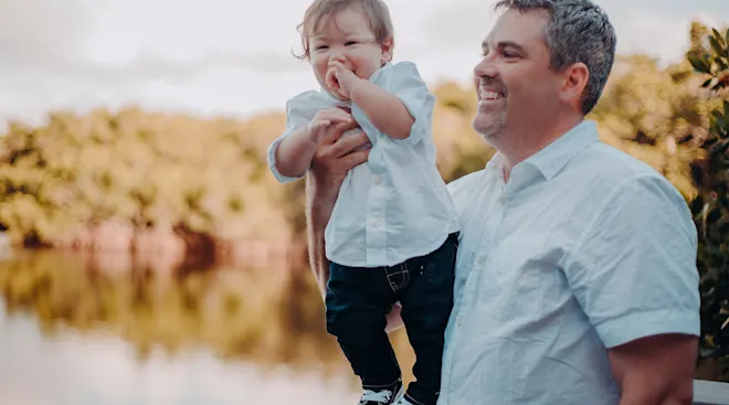 dad smiling and holding baby outside