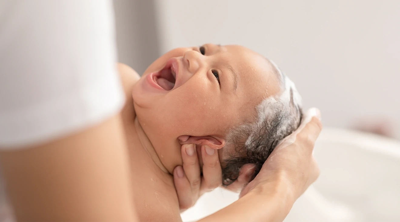 mother putting baby shampoo on baby during bath time