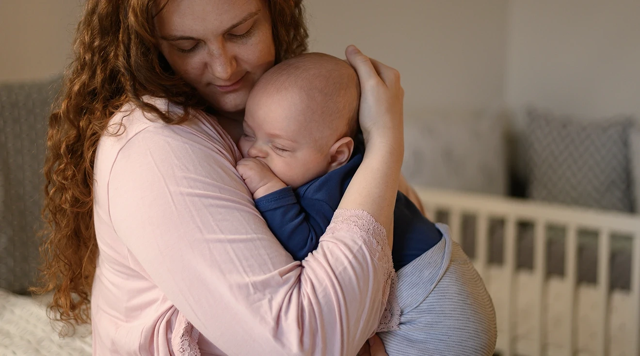 mother holding sleeping baby at home