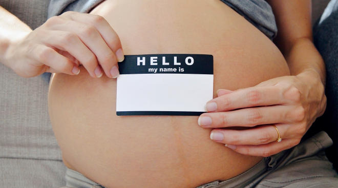 pregnant woman holding name tag over her belly