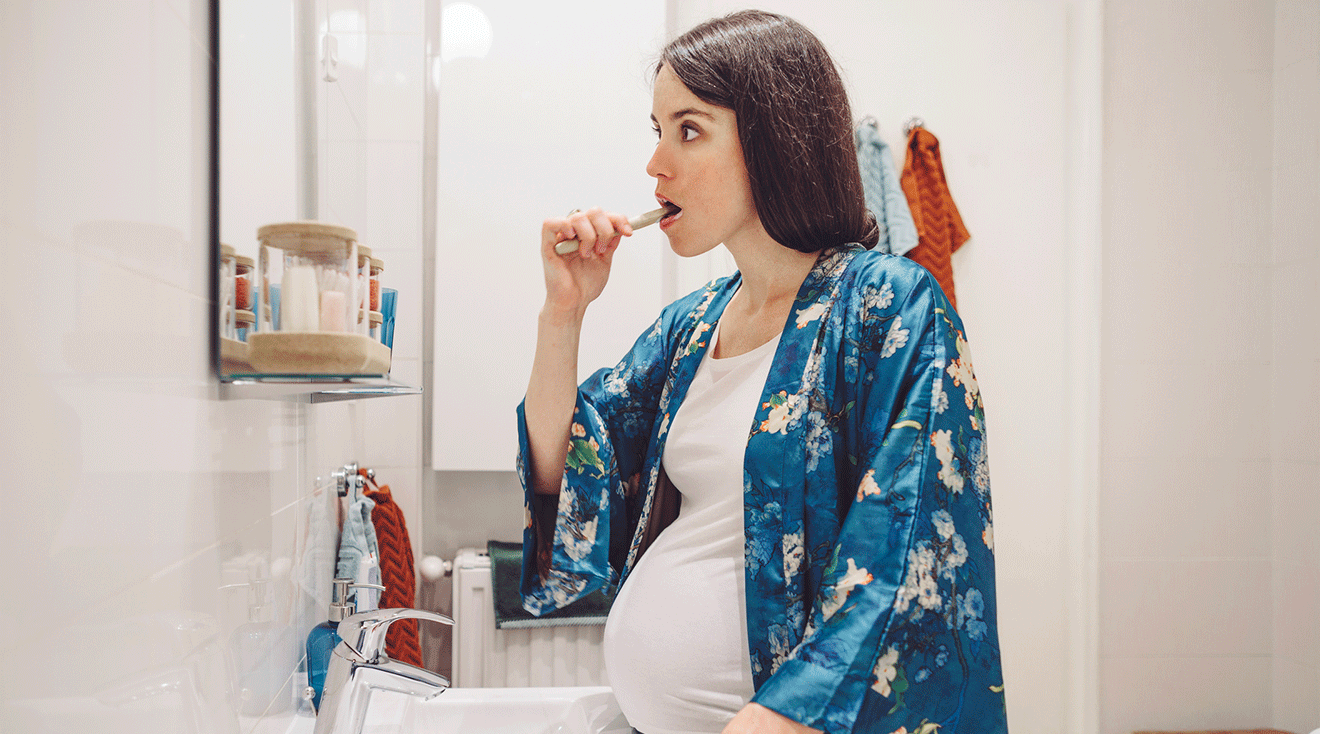 pregnant woman brushing teeth in bathroom at home