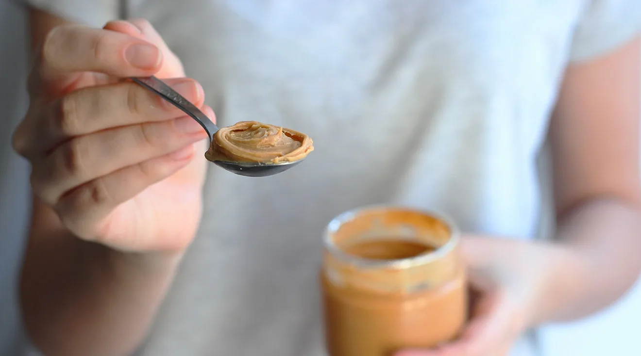 woman holding spoonful of peanut butter