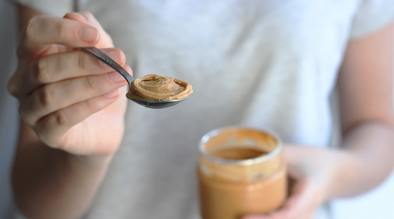 woman holding spoonful of peanut butter