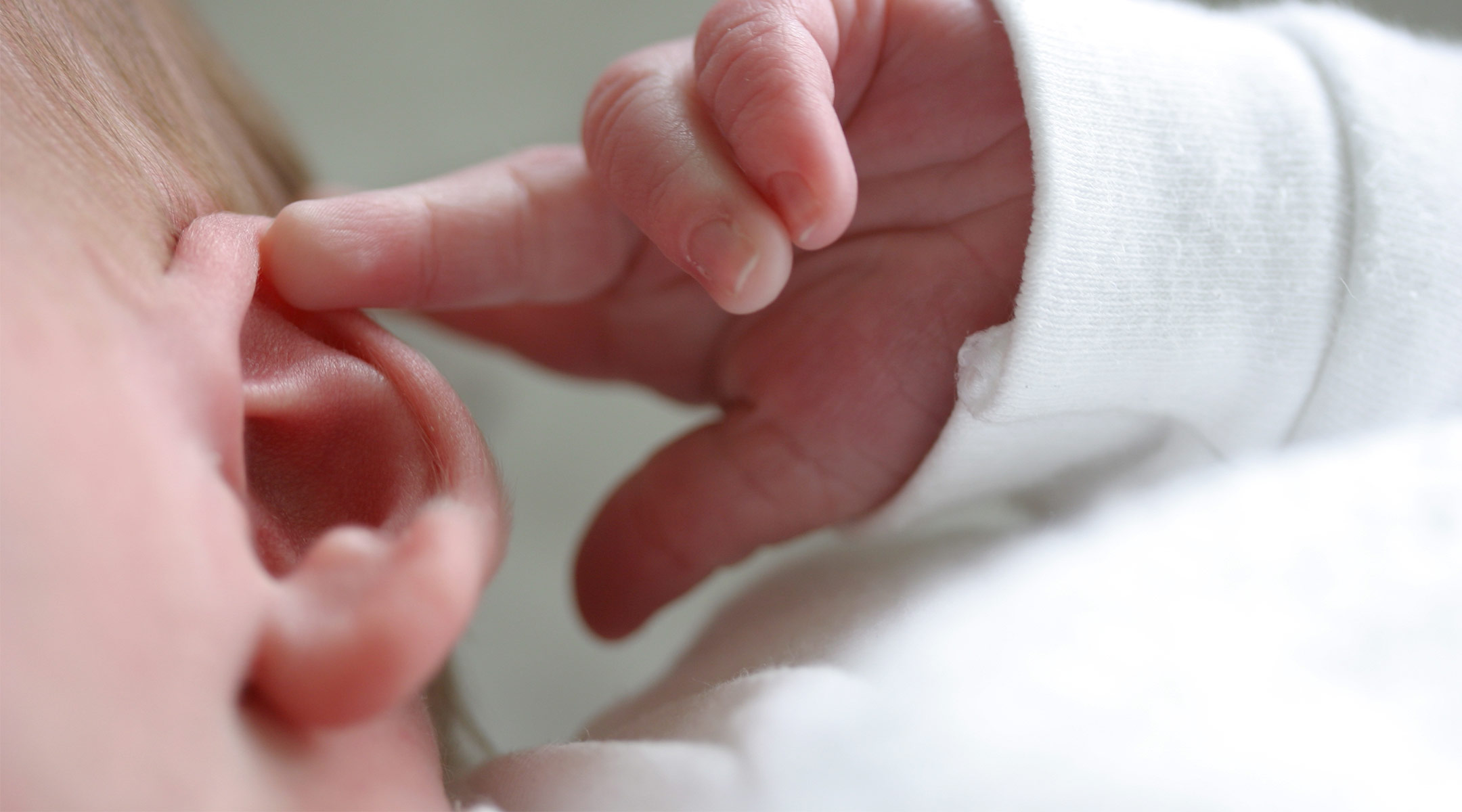 newborn baby touching his ear