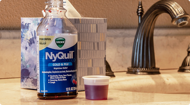 A bottle of Nyquil medicine sitting on the counter next to a bathroom sink. 