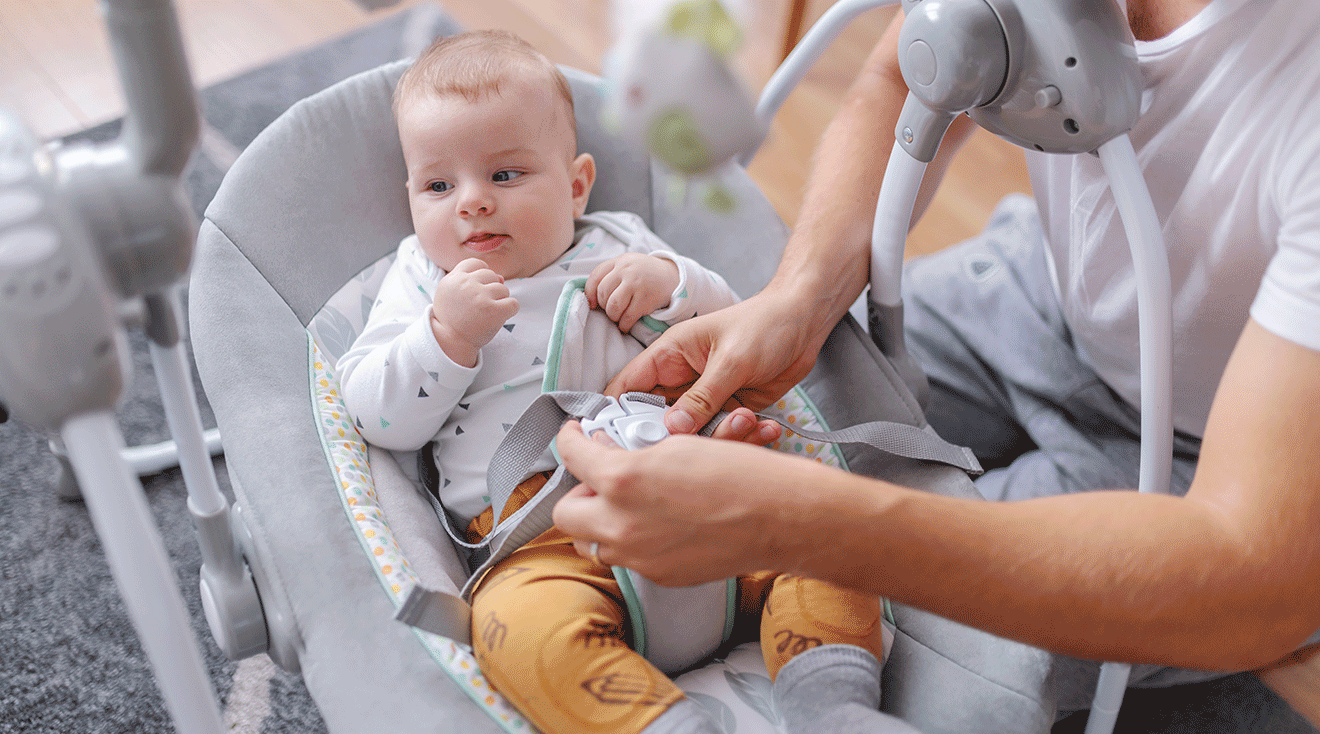 dad strapping baby into rocker