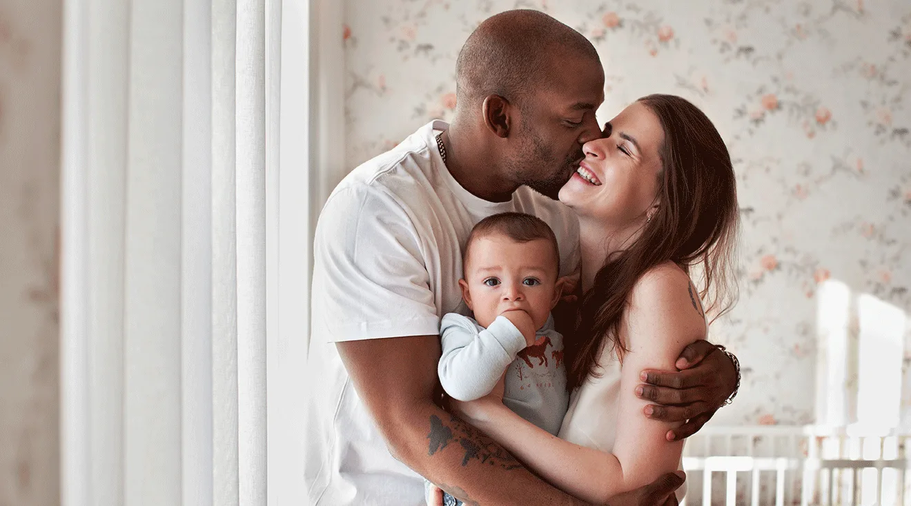 dad hugging mom and infant at home