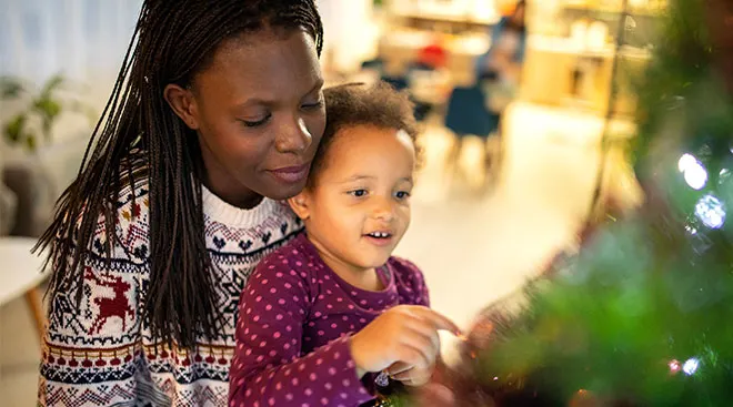 mom holding her young child by the christmas tree