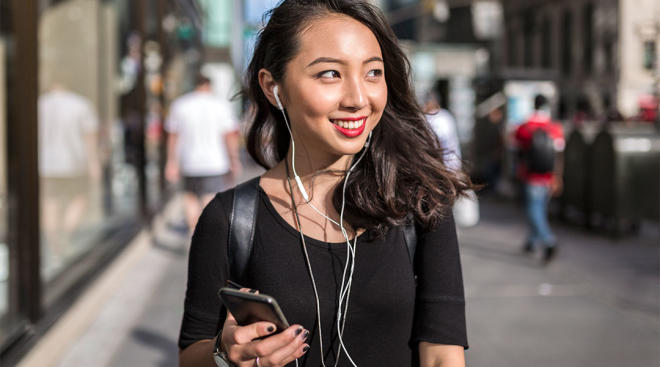 young woman smiling coyly and and walking through city streets