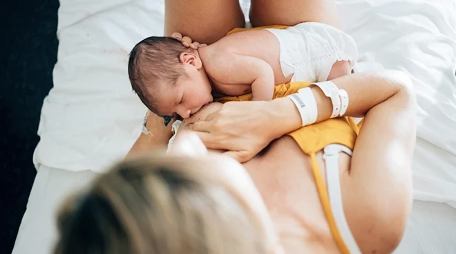 overhead view of mother breastfeeding baby on bed at home