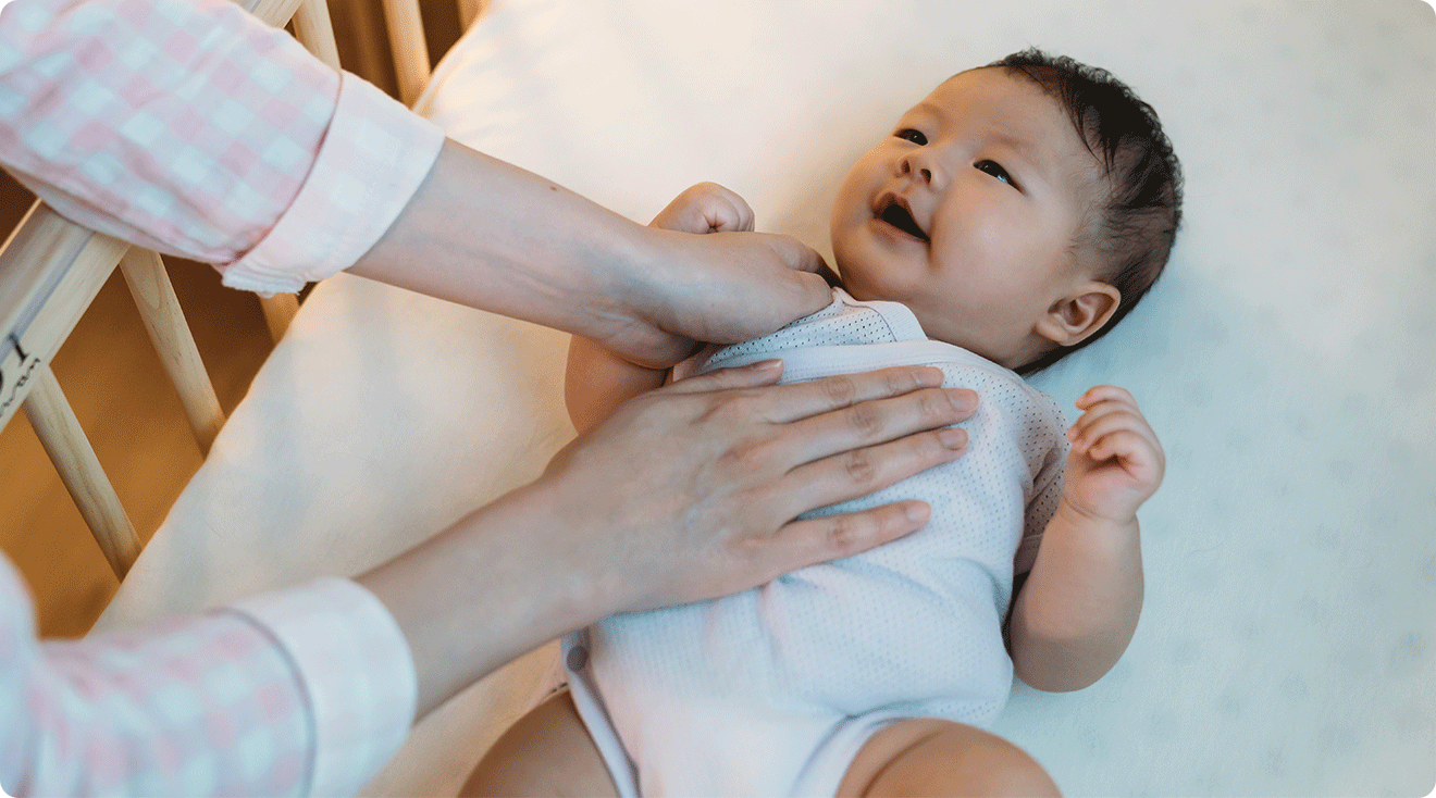 mom soothing baby in crib at night