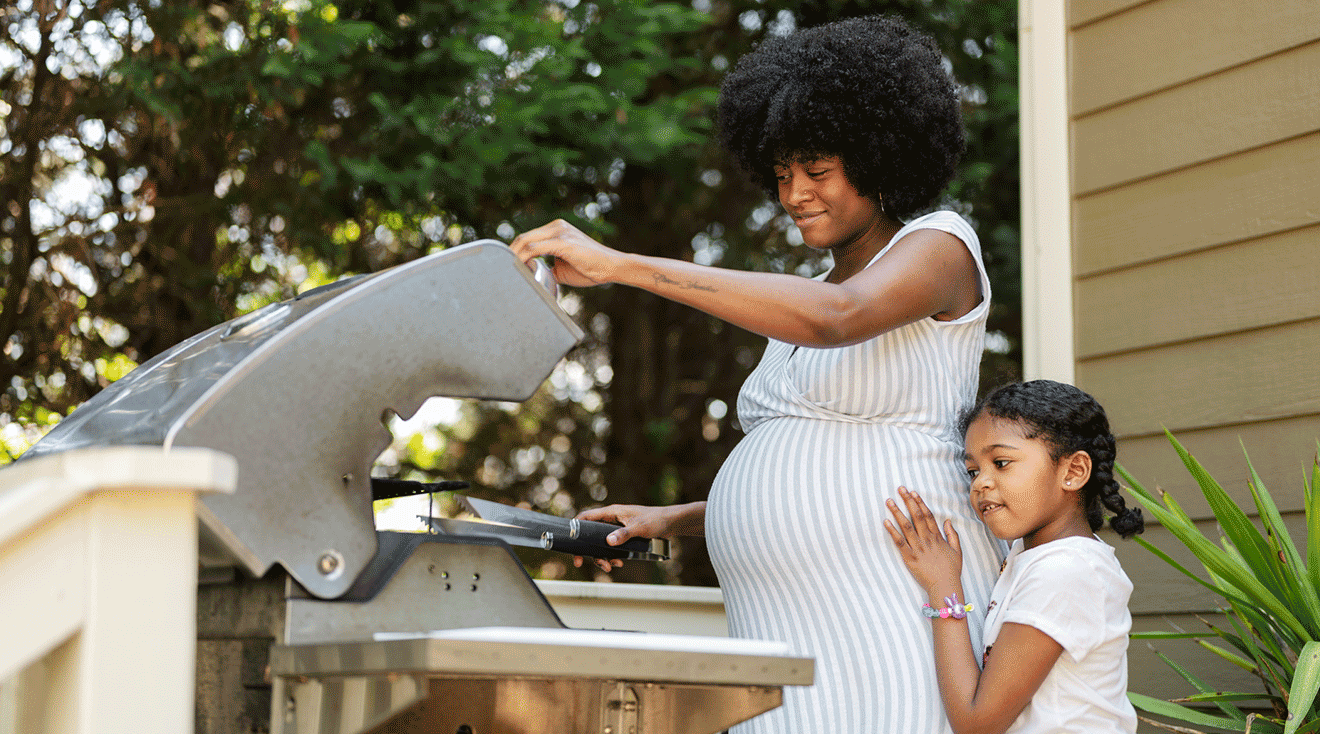 pregnant mom and daughter using the barbecue on a summer day