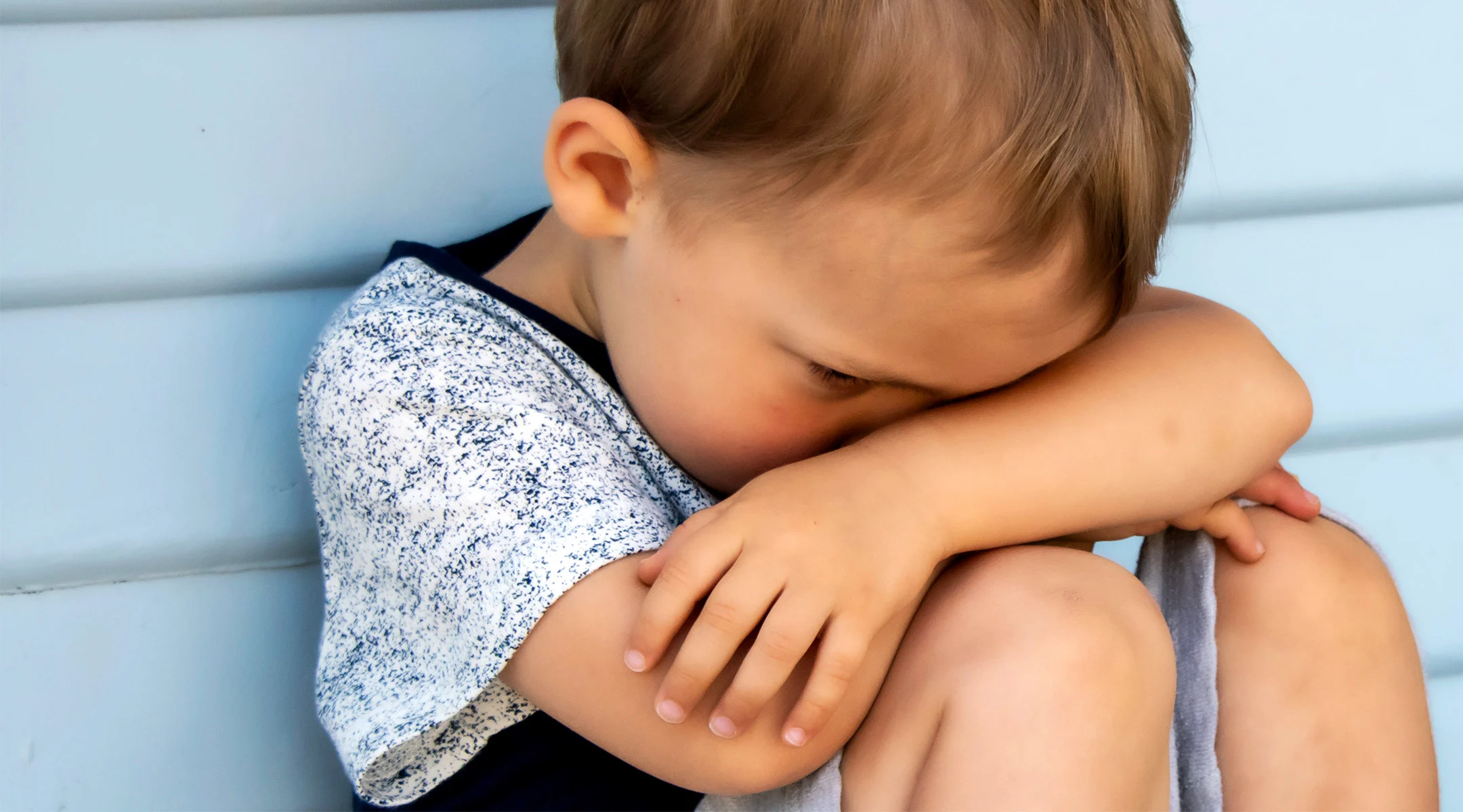 upset toddler with sitting with his head down