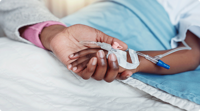 child hand with IV in hospital bed